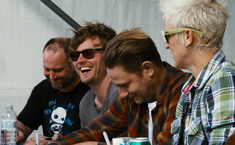 Members of Australian alt-rock band Jebediah laughing and signing autographs during a fan meet-and-greet event.